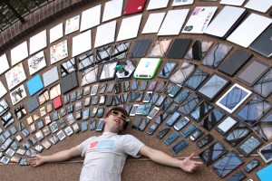 Man laying in half circle eo phones, tablets, and laptops